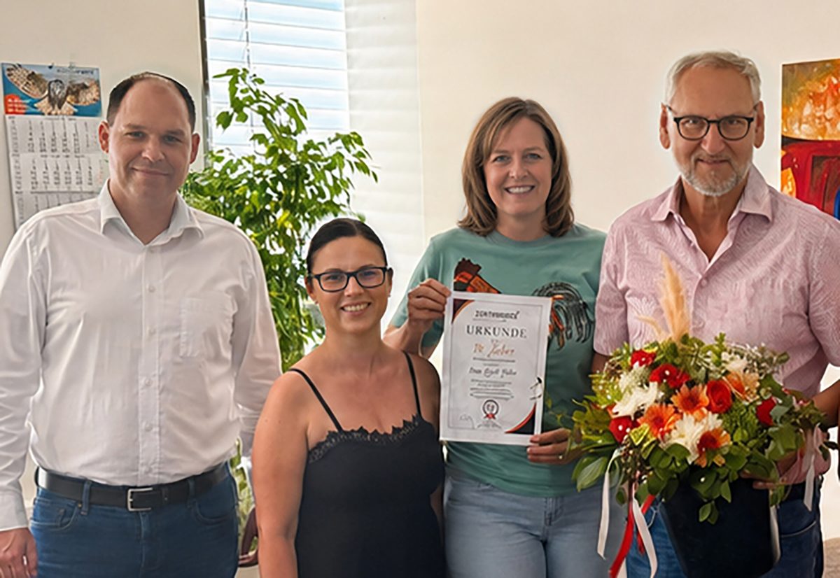 Brigitte mit Urkunde und Blumenstrauß bei der Feier ihres zehnjährigen Jubiläums bei zeitconcept, gemeinsam mit drei Kolleginnen und Kollegen