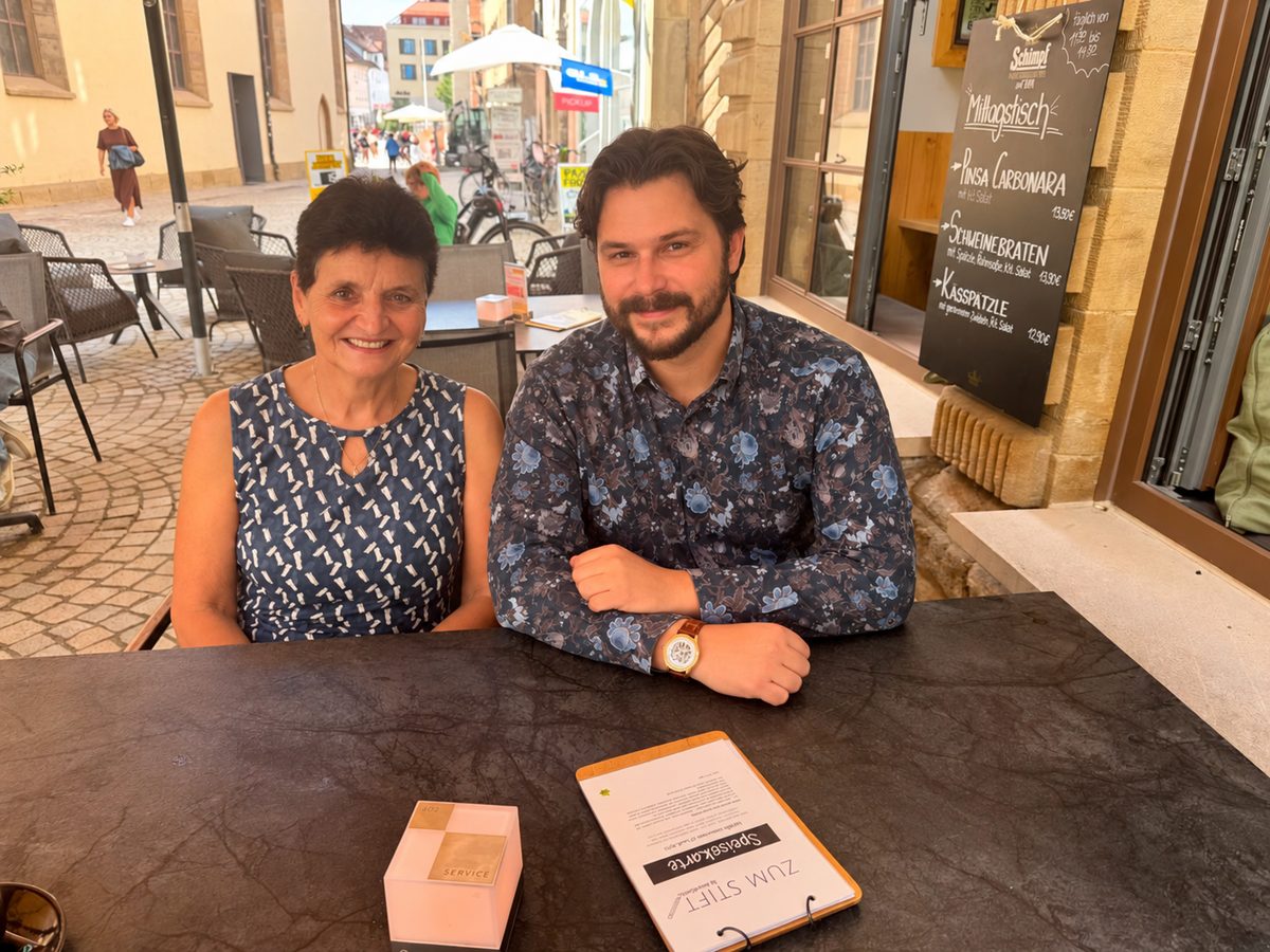 Sabine und Sebastian Jauert vom zeitconcept-Team Stuttgart sitzen beim Abschiedsfrühstück an einem Tisch vor einem Lokal in der Altstadt von Rottenburg
